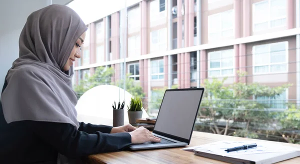 Happy arab woman freelancer chatting with clients on laptop, sitting at cafe, empty spac