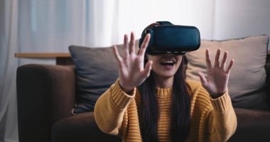 Asyalı kadın evde eğlenmek için video oyunu oynuyor, Asyalı kadın tatilde evde neşeli. Mutlu kadın metaverse VR teknoloji konsepti oynuyor