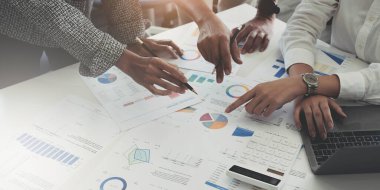 Bir grup iş adamı bir araya gelerek iş karlarını değerlendirmek için grafiğe işaret ediyorlar.