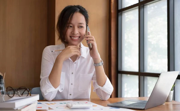 Asian business woman have the joy of talking on the phone, laptop and tablet on the office desk