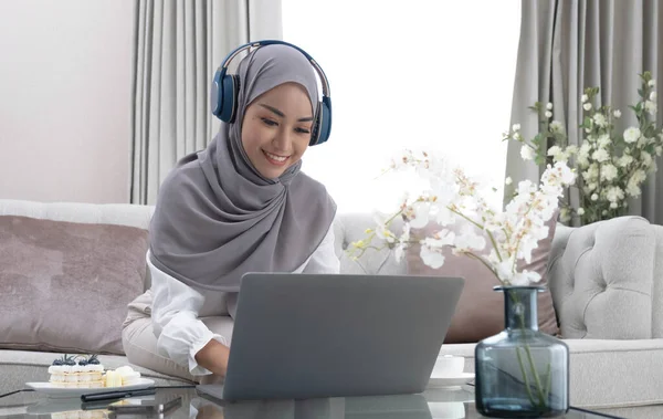 Online Tutoring. Young muslim woman teacher having video call with students, talking at laptop camera, sitting on couch at hom