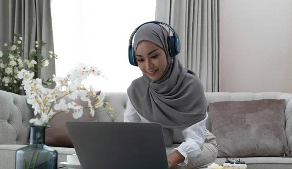 Online Tutoring. Young muslim woman teacher having video call with students, talking at laptop camera, sitting on couch at hom