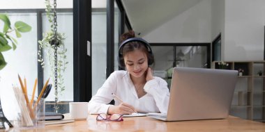Young women having online training, using laptops and wireless headse