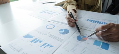 İş ekibi desteği ve toplantı konsepti. Çalışan ve mali evraklara işaret eden bir grup yatırımcı. Finans görevi