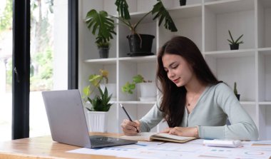 Modern ofis masasında tablet dizüstü bilgisayarla çalışan gülümseyen Asyalı bir kadının portresi, iş adamlarının online pazarlama e-pazarlama kavramı.