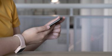 Kahve dükkanında akıllı telefon kullanan bir kadının elini kapat.