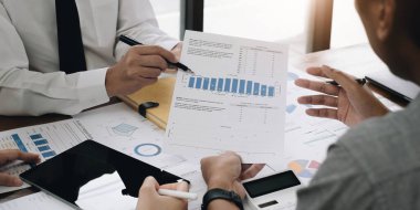 Bir grup iş adamı bir araya gelerek iş karlarını değerlendirmek için grafiğe işaret ediyorlar.