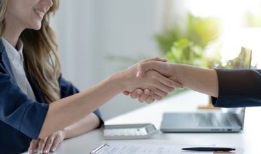 Ofiste yapılan toplantı sırasında iş ortağıyla tokalaşan tanınmayacak kadar mutlu iş kadınının yakınlaşması.