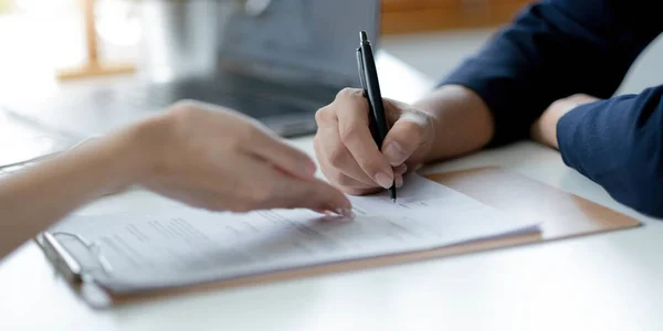 Close up of aged woman patient hand signing medical insurance contract at doctor office. Female medic show retired lady client place to put signature on healthcare coverage policy