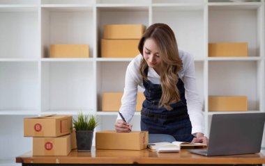 Küçük işletmeler kurma portresi KOBİ sahipleri fatura kutusu üzerinde çalışan kadın girişimciler ve kutuları paketlemek, müşterilere satmak ve çevrimiçi işletme fikirleri satmak için online siparişleri işaretlemek