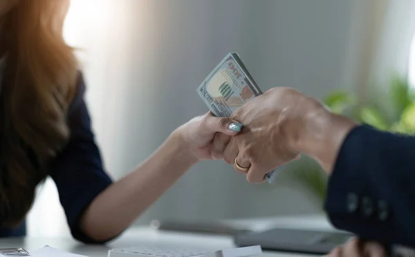 A female lawyer or business legal consultant receives a bribe or tribute from her client in the office. Corruption concept. cropped and close-up imag