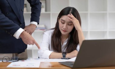 Yorgun ve sıkılmış Asyalı genç iş kadını ya da ofis çalışanı erkek patronundan iş performansı hakkında şikayet alıyor.