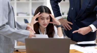 Hüsrana uğramış ve meşgul Asyalı genç iş kadını ya da meslektaşlarıyla çalışan kadın işçi.