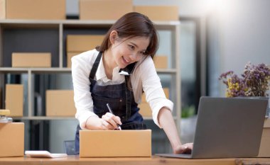 Kadın küçük işletme sahibi, telefon yoluyla müşteriler için ürünleri kontrol ediyor