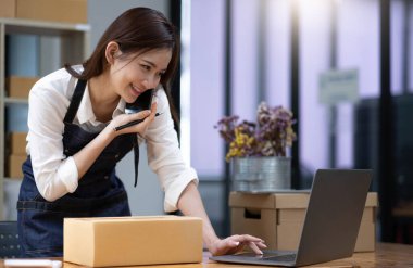 Kadın küçük işletme sahibi, telefon yoluyla müşteriler için ürünleri kontrol ediyor