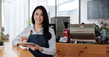 Başlangıçta başarılı olan küçük işletme sahibi, kafeterya restoranında elinde tablet akıllı telefonuyla güzellik kızı standı açmıştı. Kahveci Asyalı kadının portresi. KOBİ girişimci satıcı iş konsepti