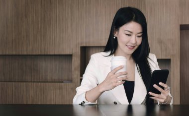 Asyalı iş kadını rahat ol ve ofiste cep telefonu çalmaktan zevk al.