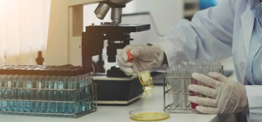 Closeup biochemistry laboratory research, Chemist is analyzing sample in laboratory with Microscope equipment and science experiments glassware containing chemical liquid