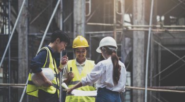 A diverse team of experts are planning on the construction site. Real estate project with civil engineers, architects, business investors and the general staff are discussing the details of the plans