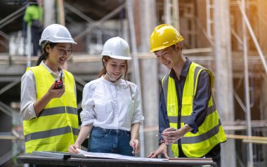 A diverse team of experts are planning on the construction site. Real estate project with civil engineers, architects, business investors and the general staff are discussing the details of the plans