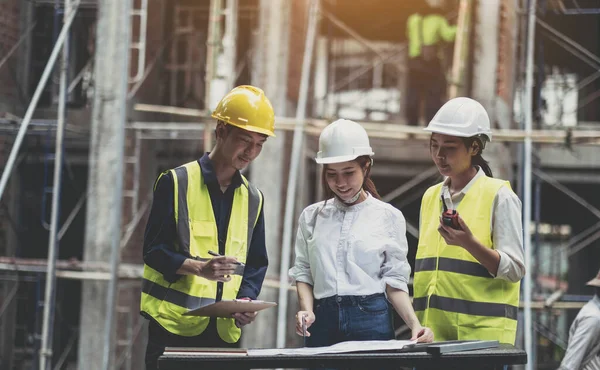 A diverse team of experts are planning on the construction site. Real estate project with civil engineers, architects, business investors and the general staff are discussing the details of the plans