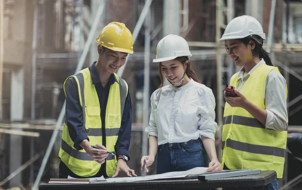 A diverse team of experts are planning on the construction site. Real estate project with civil engineers, architects, business investors and the general staff are discussing the details of the plans