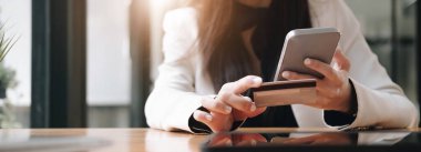 Kredi kartı ve akıllı telefonu tutan kadınların ellerini kapat. İnternetten ödeme yapan genç bir kadın. Bankacılık hizmetini kullanan, bilgi giren, alışveriş yapan, internet mağazasından sipariş veren, güvenli ödeme yapan genç bir kadın.