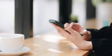 Close up of a woman using mobile smart phone at cafe