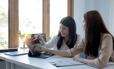 Entrepreneur Asian two businesswoman discussing new business project in tablet in modern Meeting In Modern Office, Asian business casual concept