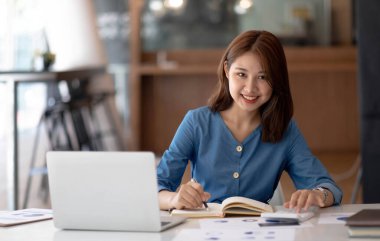 Young beautiful woman using her laptop while sitting in a chair at her working place, Small business owner people employee freelance online sme marketing e-commerce telemarketing concept
