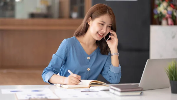 Asian businesswoman in formal suit in office happy and cheerful during using smartphone and workin