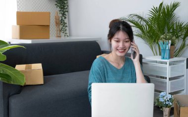 Closeup startup small business SME, Entrepreneur owner using smartphone or tablet taking receive and checking online purchase shopping order to preparing pack product box. Selling online ideas concep
