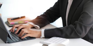 Close-up woman's hands work and typing on laptop computer with digital tablet on the desk at workplace