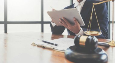 justice and law concept.Male judge in a courtroom the gavel,working with digital tablet  on wood table in offic