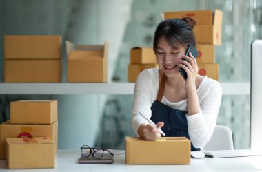 Küçük işletme sahipleri iş yerinde bilgisayar ve telefon kullanıyorlar, satıcılar üretim siparişlerini kontrol ediyorlar. Ürünleri müşterilere yollamak, nakliye fikirleri satmak için paketleyin