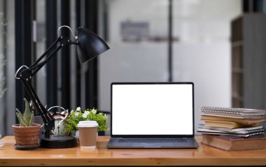 Boş ekran, kahve fincanı, kalem tutacağı, defter ve ev bitkisi olan bir bilgisayar.