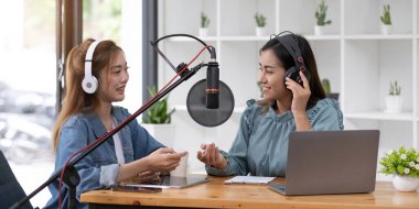Smile two asian young woman, man radio hosts in headphones, microphone while talk, conversation, recording podcast in broadcasting at studio together. Technology of making record audio concept