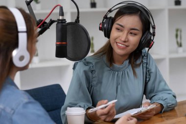 Smile two asian young woman, man radio hosts in headphones, microphone while talk, conversation, recording podcast in broadcasting at studio together. Technology of making record audio concept