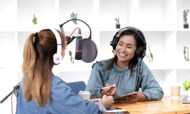 Smile two asian young woman, man radio hosts in headphones, microphone while talk, conversation, recording podcast in broadcasting at studio together. Technology of making record audio concept