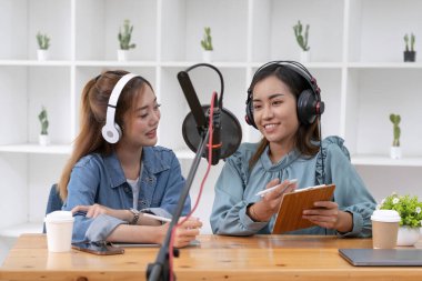 Smile two asian young woman, man radio hosts in headphones, microphone while talk, conversation, recording podcast in broadcasting at studio together. Technology of making record audio concept