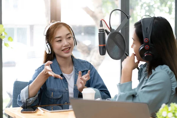 Smile two asian young woman, man radio hosts in headphones, microphone while talk, conversation, recording podcast in broadcasting at studio together. Technology of making record audio concept