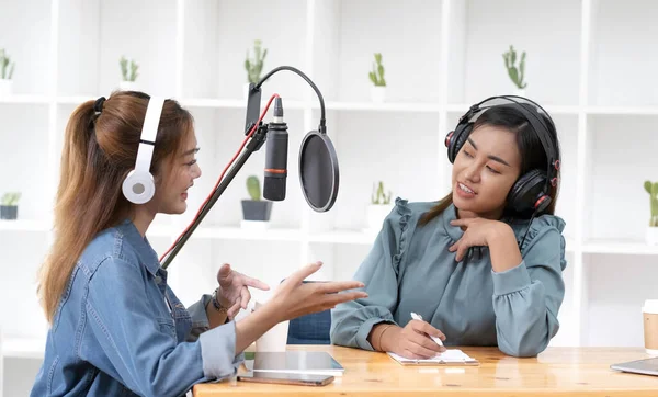 Smile two asian young woman, man radio hosts in headphones, microphone while talk, conversation, recording podcast in broadcasting at studio together. Technology of making record audio concept
