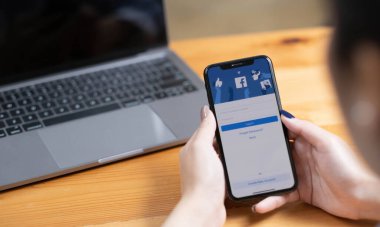 CHIANG MAI ,THAILAND - AUG 18, 2022 : Woman hand holding iPhone X to use facebook with new login screen.Facebook is a largest social network and most popular social networking site in the world