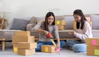 Startup small business owner working with computer at workplace. Freelance two woman seller check product order. Packing goods for delivery to customer. Online selling. E-commerce. Online Shoppin