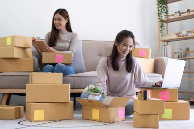Startup small business owner working with computer at workplace. Freelance two woman seller check product order. Packing goods for delivery to customer. Online selling. E-commerce. Online Shoppin