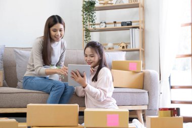 Startup small business owner working with computer at workplace. Freelance two woman seller check product order. Packing goods for delivery to customer. Online selling. E-commerce. Online Shoppin