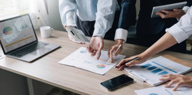 Closeup of businesspeople hands pointing a pie chart together on the paperwor