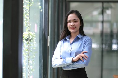 Genç, kendine güvenen Asyalı iş kadını lideri, başarılı girişimci, zarif profesyonel şirket yöneticisi. Asyalı iş kadını kollarını kavuşturarak ofiste duruyor.. 