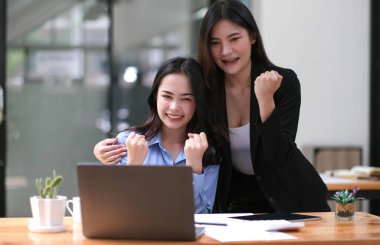 Genç Asyalı iş adamları yaratıcı iş adamları ofiste başarılı iş arkadaşları başarıyı ve başarı kavramını kutlayan ortaklık çalışmalarından mutluluk duyarlar..