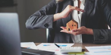 Elinde ev modeli olan kadın bir sigorta komisyoncusu. Ev koruması.